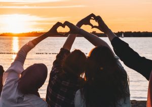 People at sunset making hearts with their hands