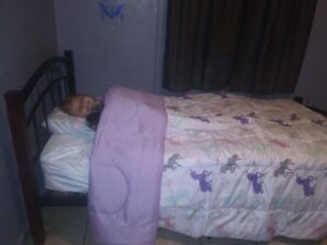 Small child under a purple unicorn blanket on a small bed.