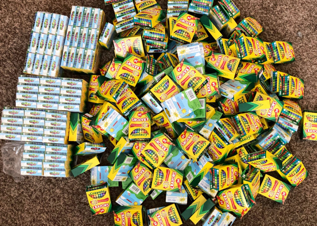 A big pile of crayons boxes is displayed on the floor.