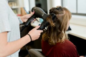 hairdresser brushing and blowdrying a brunette women