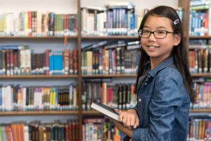 girl holding book in school library